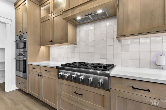 2499 E Berghan Ln, Meridian, ID 83642 - kitchen featuring extractor fan, appliances with stainless steel finishes, light countertops, tasteful backsplash, and glass insert cabinets