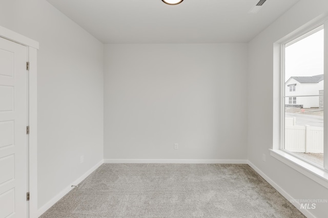 unfurnished room with baseboards and light colored carpet