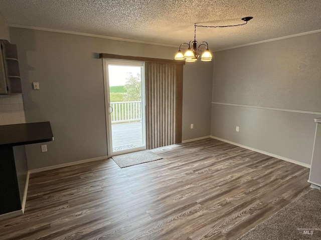 unfurnished dining area featuring crown molding, dark wood-style floors, a textured ceiling, and an inviting chandelier