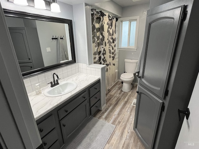 full bath with tasteful backsplash, a shower with shower curtain, toilet, wood finished floors, and vanity