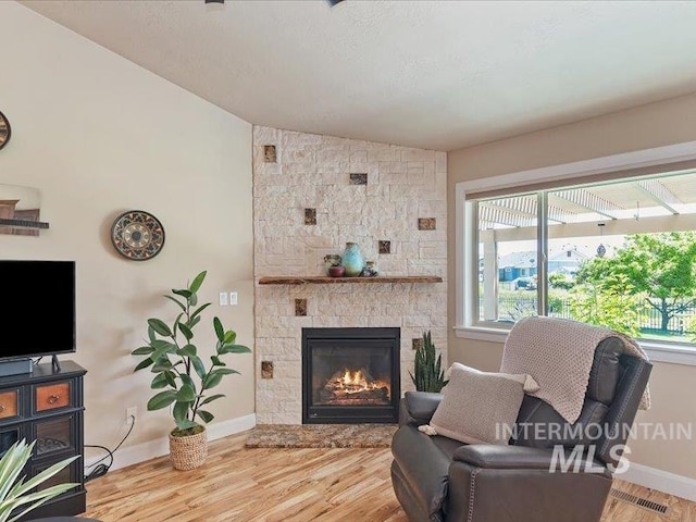 5747 W Rotherham Dr, Eagle, ID 83616 - living room featuring lofted ceiling, a stone fireplace, and wood finished floors