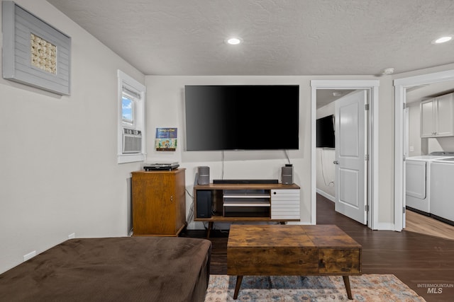 living room featuring washing machine and dryer, cooling unit, a textured ceiling, and dark hardwood / wood-style flooring