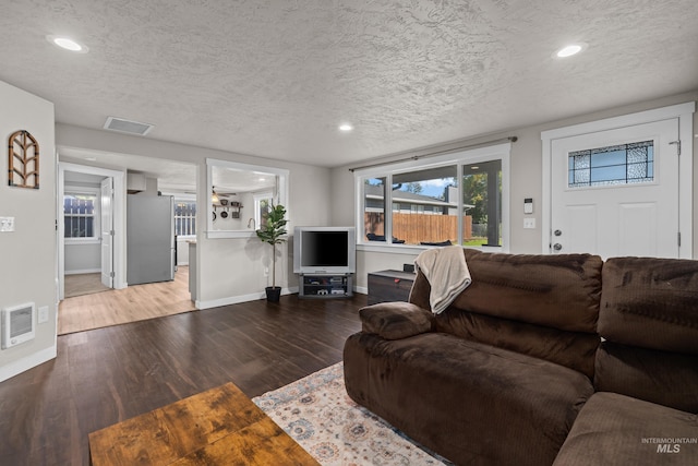 living room with wood-type flooring, heating unit, and a textured ceiling