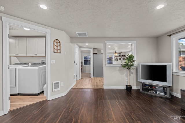 unfurnished living room with a textured ceiling, ceiling fan, separate washer and dryer, and dark hardwood / wood-style flooring