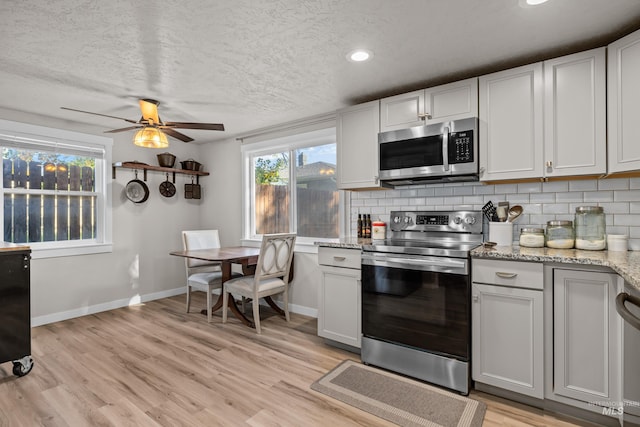 kitchen with ceiling fan, tasteful backsplash, white cabinetry, appliances with stainless steel finishes, and light hardwood / wood-style floors