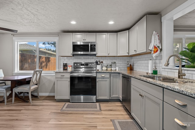 kitchen with decorative backsplash, appliances with stainless steel finishes, sink, and light wood-type flooring