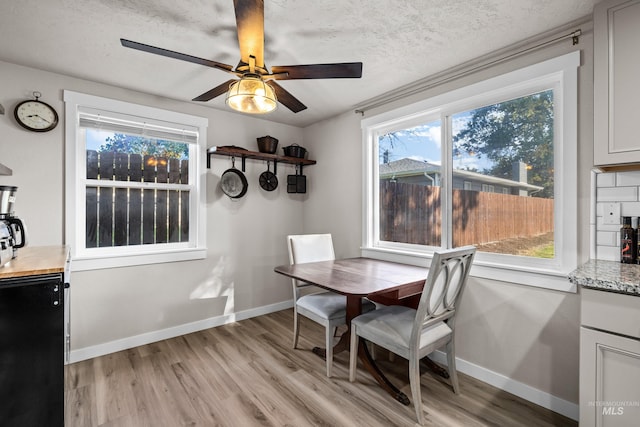 dining area featuring light hardwood / wood-style floors, a textured ceiling, and ceiling fan