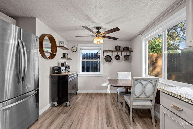 dining room with ceiling fan, light hardwood / wood-style floors, and a textured ceiling