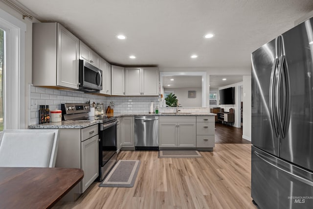 kitchen with stainless steel appliances, light hardwood / wood-style floors, and gray cabinets