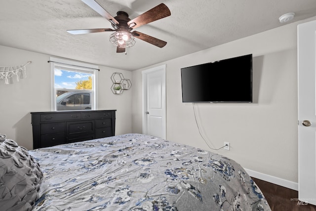 bedroom with ceiling fan, a textured ceiling, and dark wood-type flooring