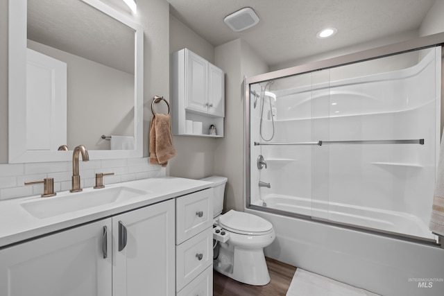 full bathroom with vanity, wood-type flooring, tasteful backsplash, combined bath / shower with glass door, and toilet