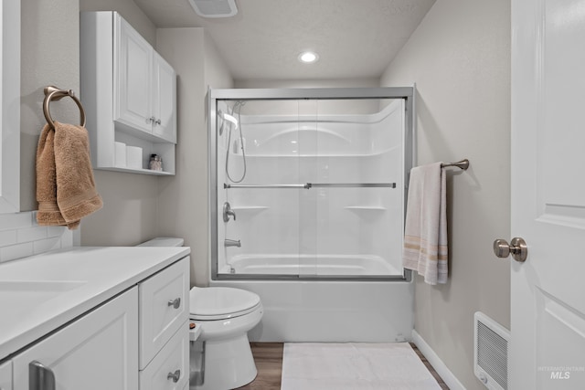 full bathroom featuring vanity, wood-type flooring, combined bath / shower with glass door, toilet, and a textured ceiling