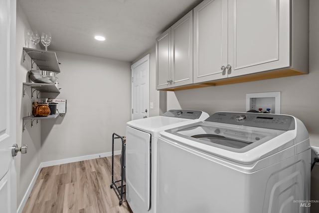 laundry area featuring light hardwood / wood-style floors, separate washer and dryer, and cabinets