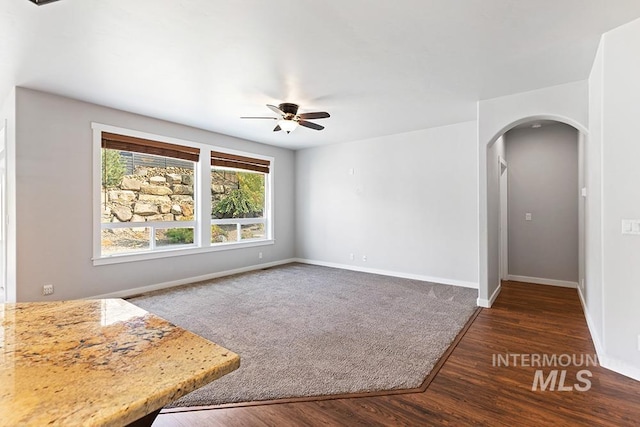 unfurnished living room featuring ceiling fan and dark hardwood / wood-style floors