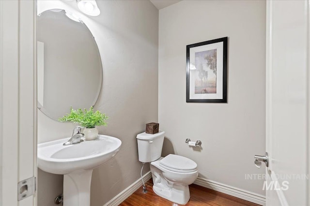 half bathroom with toilet, baseboards, and wood finished floors