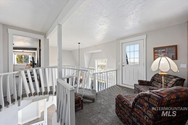 interior space with a notable chandelier, a textured ceiling, and carpet flooring