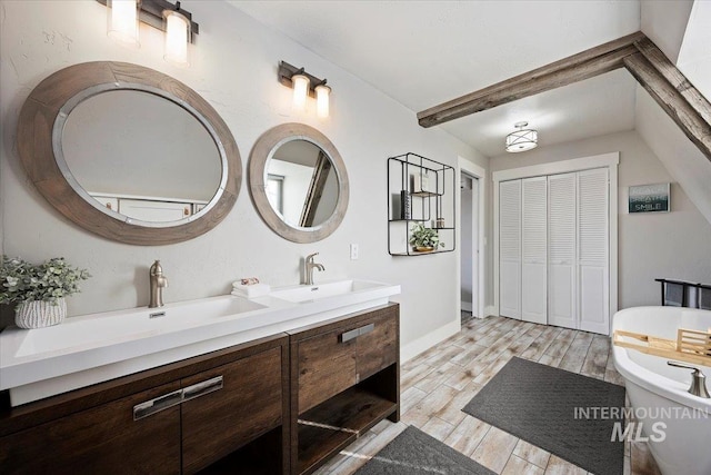 bathroom featuring double vanity, a freestanding tub, wood finish floors, and a sink