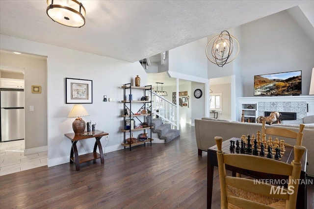 dining area featuring a chandelier, stairs, a fireplace, wood finished floors, and a textured ceiling