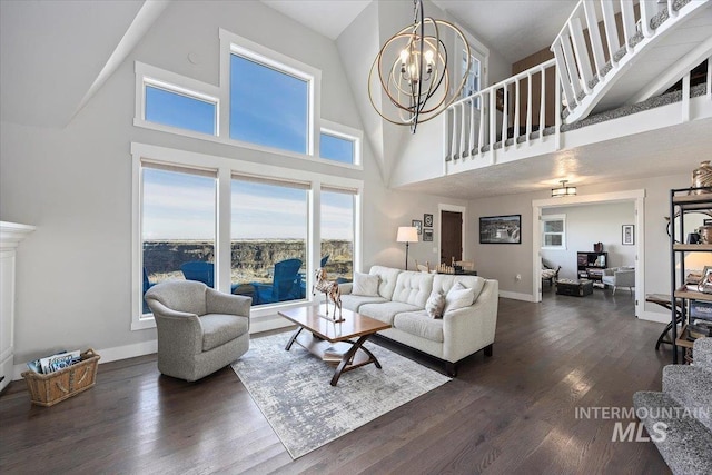 living room featuring a notable chandelier, a high ceiling, baseboards, and dark wood-style flooring