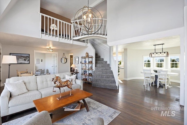 living room with stairway, a high ceiling, a chandelier, and dark wood-style flooring