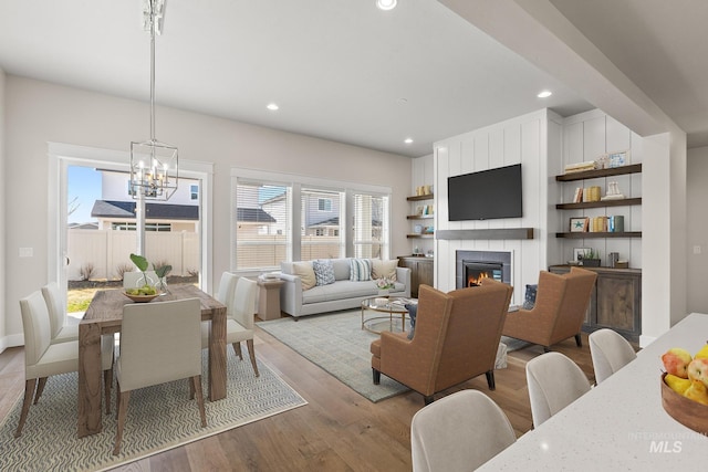 living area with light wood finished floors, recessed lighting, a large fireplace, and an inviting chandelier