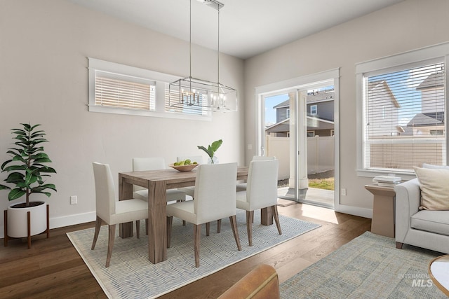 dining space featuring baseboards, an inviting chandelier, and dark wood-style flooring