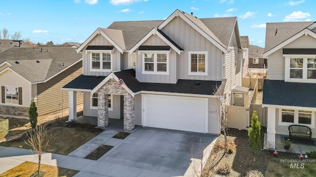 view of front facade featuring stone siding, board and batten siding, concrete driveway, and an attached garage