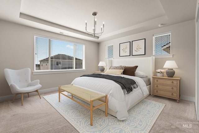 bedroom featuring a tray ceiling, light colored carpet, baseboards, and a chandelier