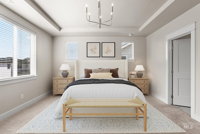 bedroom with baseboards, a raised ceiling, a notable chandelier, and light colored carpet