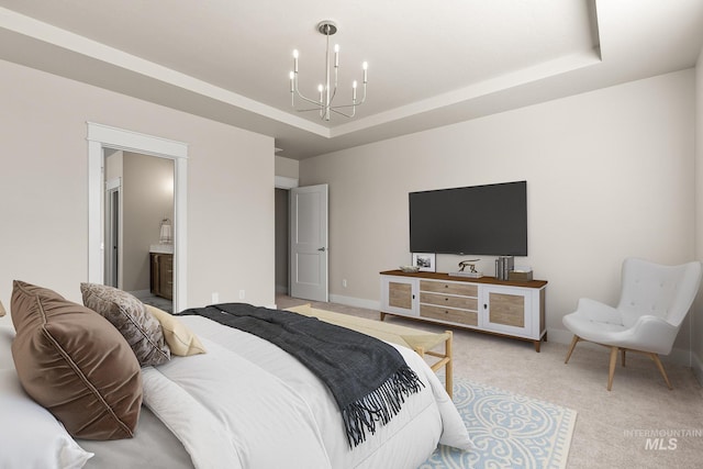 bedroom featuring connected bathroom, a tray ceiling, a chandelier, and carpet flooring