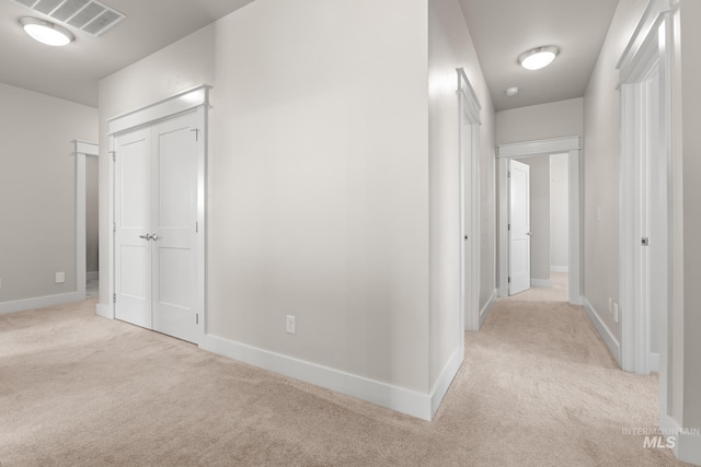 hall with carpet flooring, baseboards, and visible vents