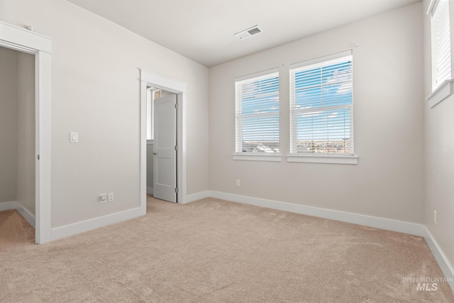 unfurnished bedroom with visible vents, baseboards, and light colored carpet