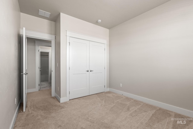 unfurnished bedroom featuring visible vents, light carpet, baseboards, and a closet