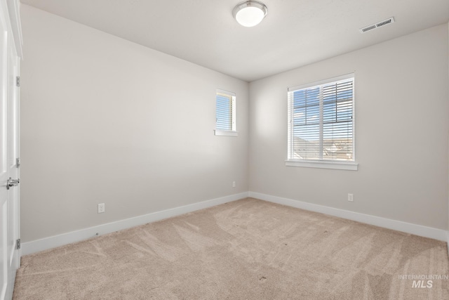 spare room featuring baseboards, visible vents, and carpet floors