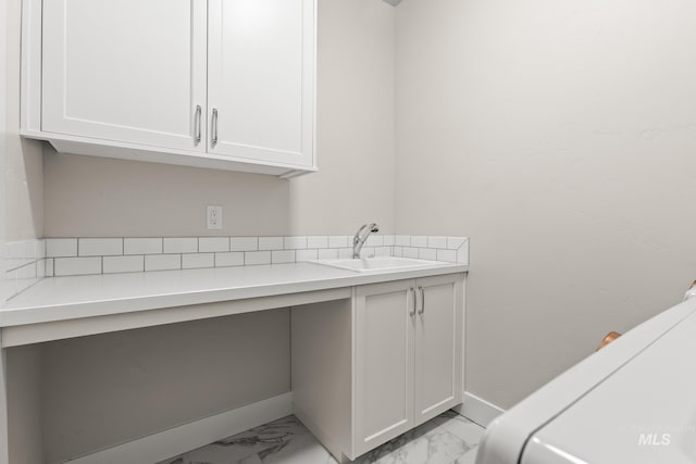 laundry area featuring baseboards, marble finish floor, and a sink