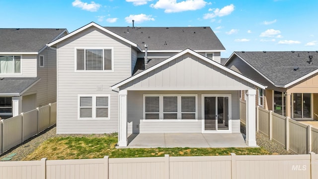 rear view of property with a patio, board and batten siding, and a fenced backyard