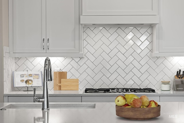 kitchen featuring tasteful backsplash, white cabinets, and stainless steel gas cooktop