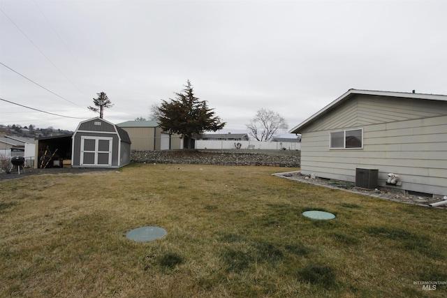 view of yard with an outbuilding, central AC, fence, and a storage shed