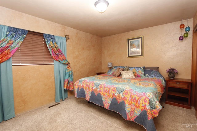 bedroom featuring a textured wall, carpet flooring, and visible vents