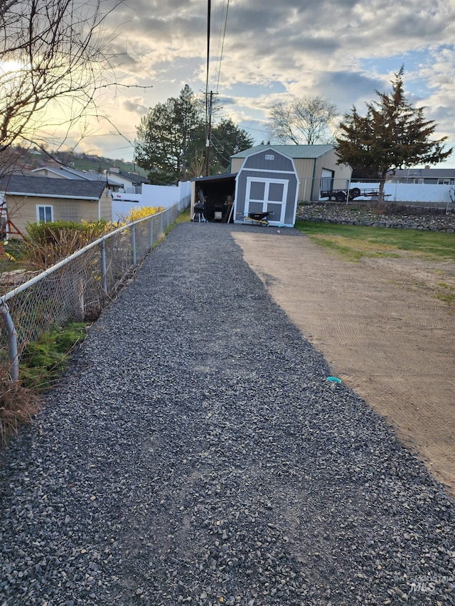 view of yard with an outbuilding, driveway, a shed, and fence