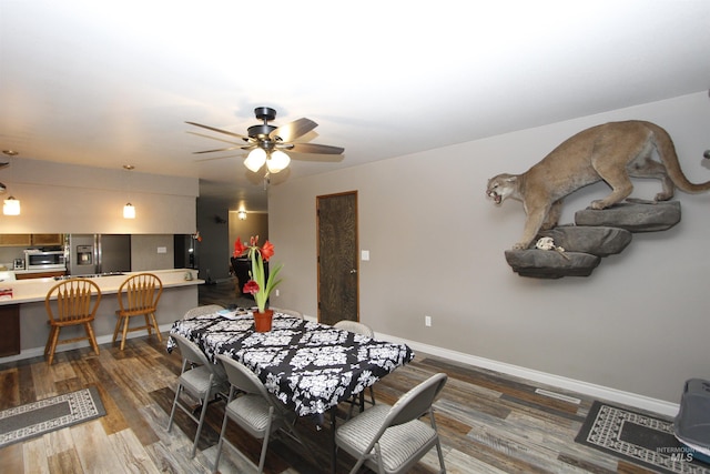 dining room with dark wood-style flooring, a ceiling fan, and baseboards