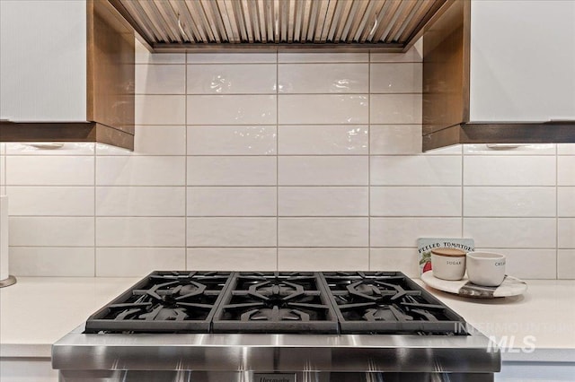 kitchen featuring tasteful backsplash, white cabinetry, exhaust hood, and stainless steel range oven