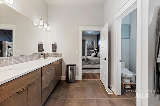 bathroom with tasteful backsplash, vanity, tile patterned flooring, and toilet