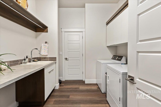 laundry area with independent washer and dryer, sink, dark wood-type flooring, and cabinets