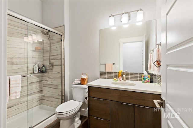 bathroom with vanity, an enclosed shower, decorative backsplash, and toilet