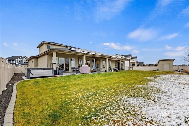 back of property featuring a hot tub, a patio area, and solar panels