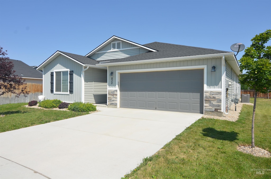 view of front of house featuring a front lawn, cooling unit, and a garage