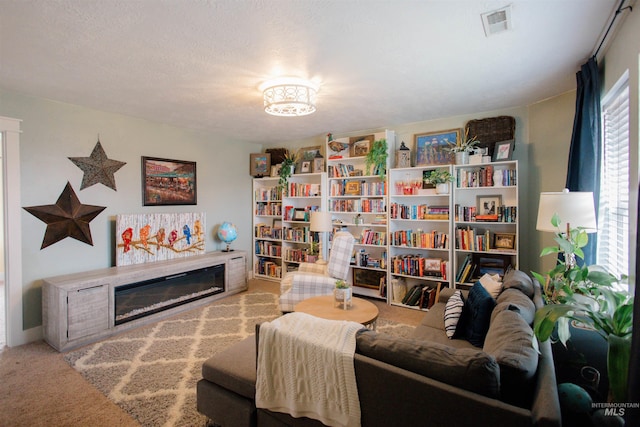carpeted living area featuring a glass covered fireplace
