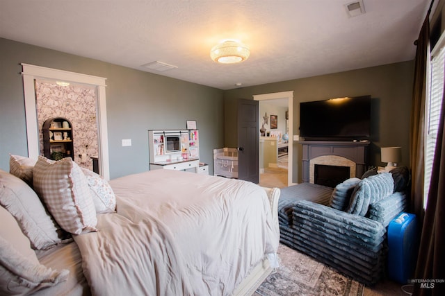 bedroom with a brick fireplace and light colored carpet