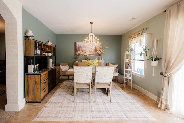 dining room featuring arched walkways, a chandelier, baseboards, and light tile patterned flooring